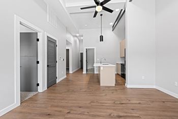 A long, empty hallway with a ceiling fan and wooden floors.